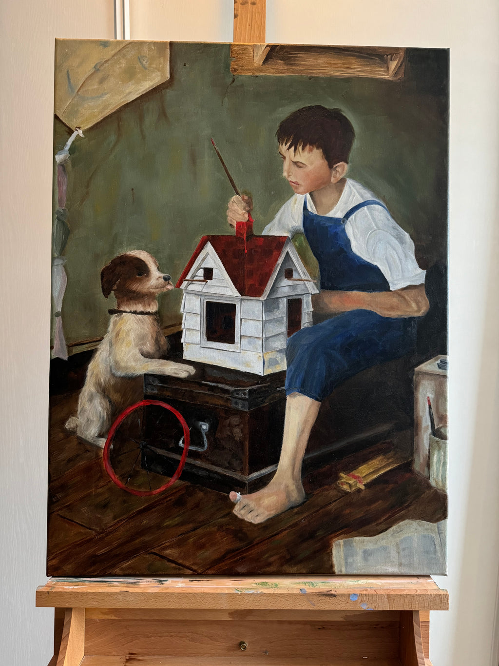 Boy paints small wooden house with dog