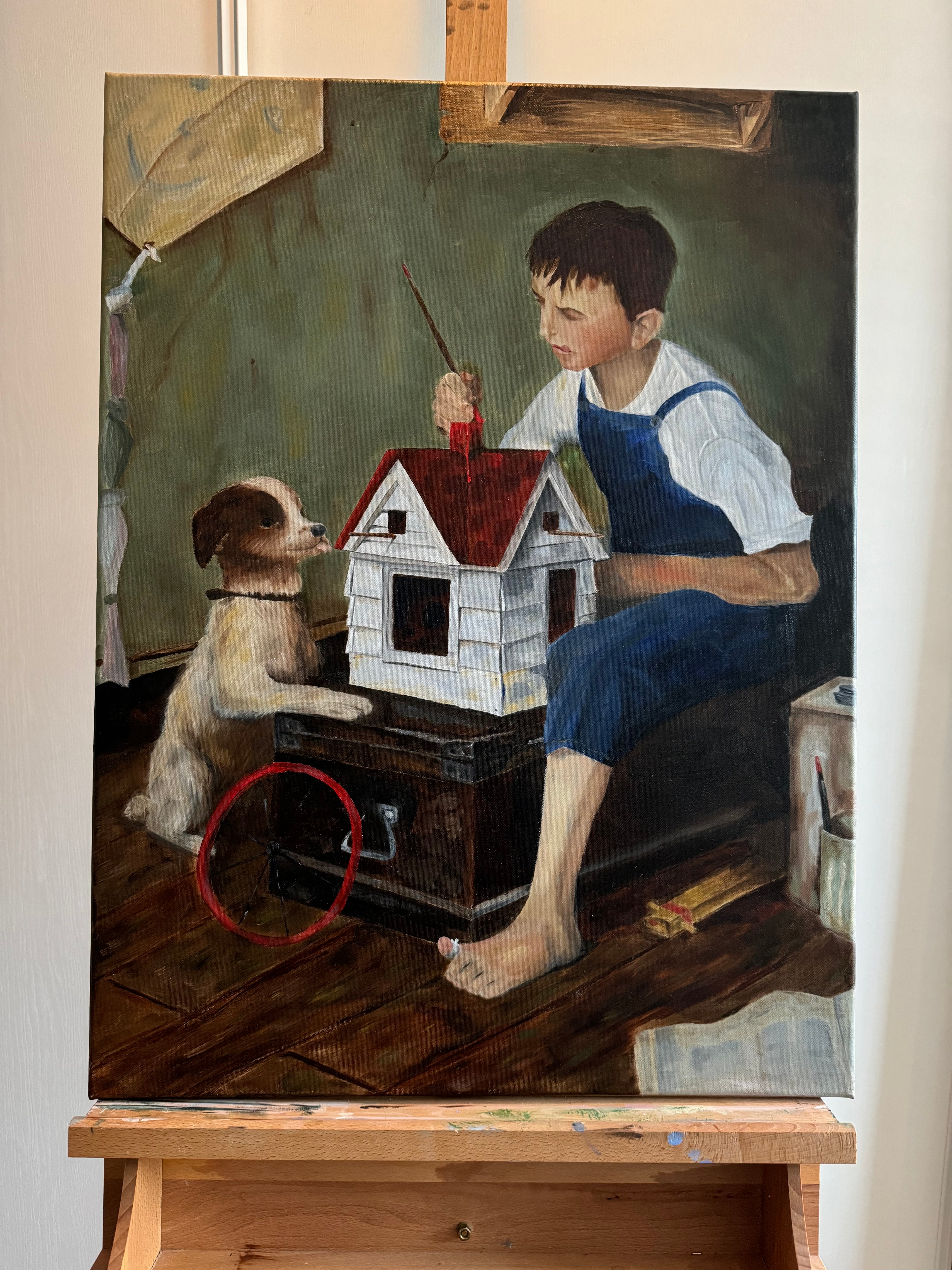 Boy paints small wooden house with dog